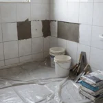 Banheiro em reforma com azulejos e ferramentas mantendo o imóvel habitável
