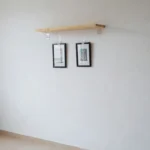 Prateleira e quadros pendurados em parede de apartamento alugado sem danificar a superfície